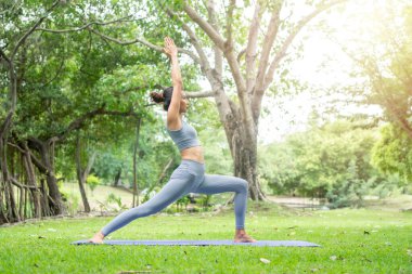 Bahçede yoga yapan genç bir kadının portresi. Yaşam tarzı uygunluğu ve sağlıklı olma kavramı. Asyalı kadınlar parkta yoga yapıyorlar..