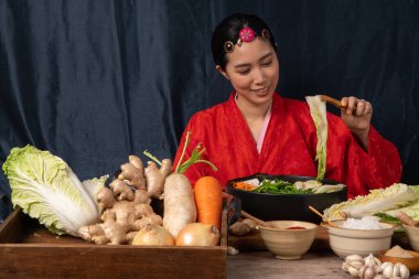 Geleneksel Kore kostümü giyen Asyalı kadınlar taze kızartma ve kimchi malzemelerini tuz, sarımsak, gochugaru, taze sebze gibi malzemelerle karıştırıyorlar..