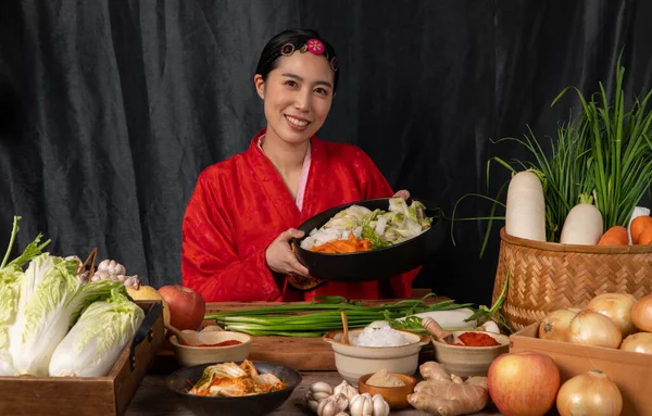 Asian women wearing Korean traditional costumes (hanbok) are mixing fresh stir-fry and kimchi ingredients with ingredients such as salt, garlic, gochugaru, fresh vegetables. — Stock Image Asian Women Wearing Korean Traditional Costumes Hanbok Mixing Fresh Stir Royalty Free Stock Images