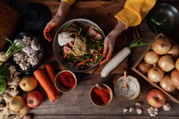 Asian women wearing Korean traditional costumes (hanbok) are mixing fresh stir-fry and kimchi ingredients with ingredients such as salt, garlic, gochugaru, fresh vegetables. — Stock Image Asian Women Wearing Korean Traditional Costumes Hanbok Mixing Fresh Stir Royalty Free Stock Photos