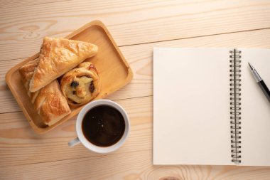 Boş bir defter ve beyaz kahve fincanlarının yanına yerleştirilmiş taze tatlıların ve turtaların en üst görüntüsü. Frenleme ve gevşeme kavramı