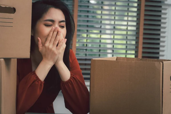 Sad Asian woman Packing belongings in a cardboard box and crying on the desk in the office After being layoff and unemployed. Concept of impact on the economic downturn And management of the failure