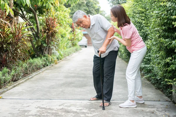 stock image Asian senior man walking in the backyard and painful inflammation and stiffness of the joints (Arthritis) and the daughter came to help support. Concept of old elderly insurance and health care