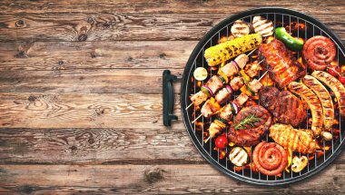 Çeşitli lezzetli ızgara et ve sebzelerin üzerine kömürün üstünde rustik ahşap zemin üzerine Barbekü ile bratwurst