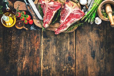 Ham kuru yaşlı t-bone biftek için taze otlar ve rustik ahşap tahta üzerinde sebze ızgara