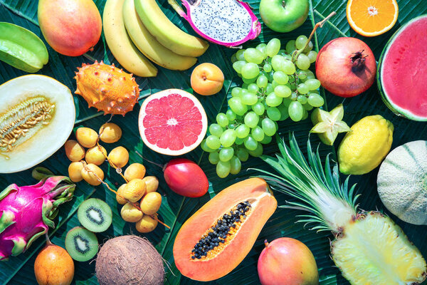 Assortment of tropical fruits on leaves of palm trees. Top view