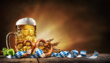 Oktoberfest beer with pretzel, wheat and hops on wooden table clipart