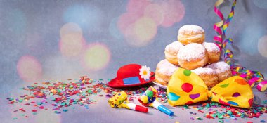 Krapfen, berliner veya çörek papyon, parti şapkası, flamalar ve konfeti ile. Renkli karnaval veya Doğum günü arka plan