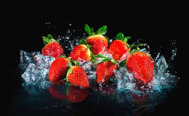 Sudaki çilekler siyah arkaplanda sıçrıyor
