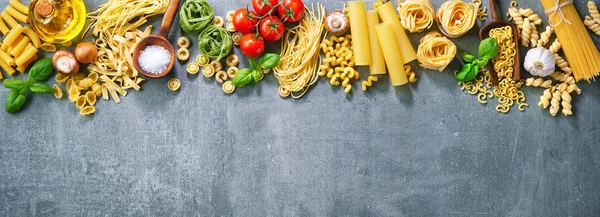 Various pasta over stone background. Top view with copy space