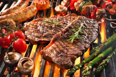 Delicious grilled meat with vegetables sizzling over the coals o clipart