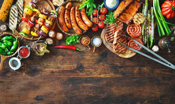 Carne a la parrilla y verduras en mesa de madera rústica —  Fotos de Stock
