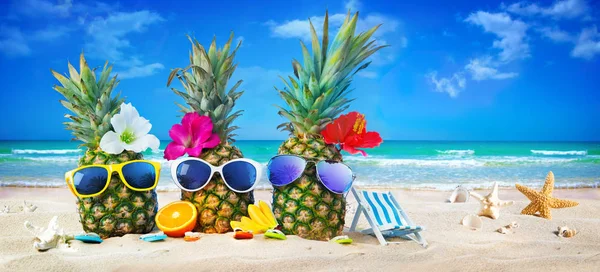 Ananas attractifs dans des lunettes de soleil élégantes sur la plage de sable ag — Photo