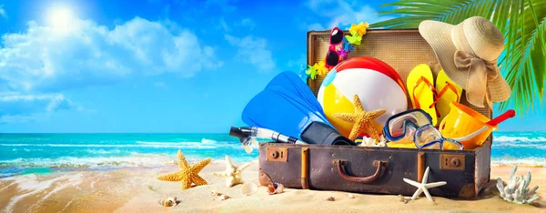 Accesorios de playa en maleta sobre arena. Concepto de vacaciones familiares —  Fotos de Stock