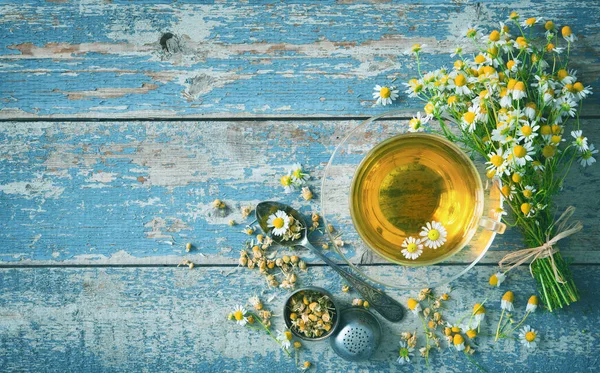 Taza de té de hierbas con flores de manzanilla en tablón de madera azul envejecido — Foto de Stock