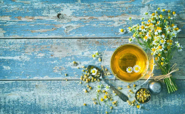 Tasse Kräutertee mit Kamillenblüten auf gealtertem blauem Holzbrett — Stockfoto