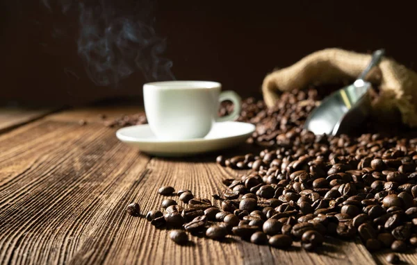Tasse Espresso mit Kaffeebohnen, Beutel, Schaufel und Dampf — Stockfoto