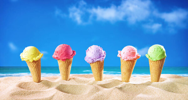 Ice creams cones and seashells in the sand on the beach with ocean landscape