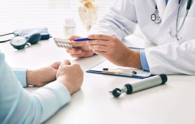 Doktor, kadın hastaya haplar hakkında danışmanlık yapıyor ve resepsiyonda oturan sağlık tedavisini engelliyor. İlaç ve sağlık hizmetleri kavramı