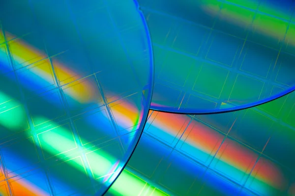 Silicon Wafers and Microcircuits - semiconductor material, such as a crystalline silicon. Detail of a silicon chip wafer reflecting different colors