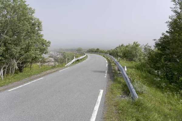 Liten väg som böjer sig mot fjord dimma nära Grunnfor, Norge — Stockfoto