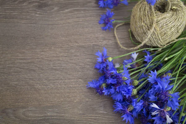 a bouquet of cornflowers, a tangle of threads, close-up on a wooden background