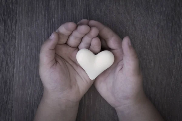 Niño Sostiene Corazón Cercano Manos Sobre Fondo Madera —  Fotos de Stock