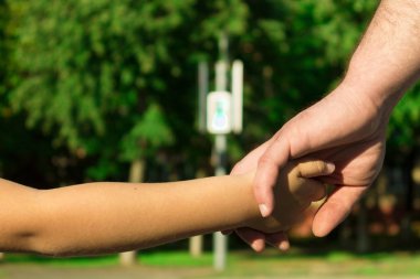Bir yaya geçidi adlı bir çocuk koruma kavramı. Bir trafik ışığı, bir geçiş. Babası oğlunun elini tutar