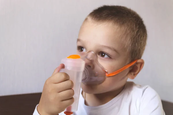 A child inhales a nebulizer at home on the bed