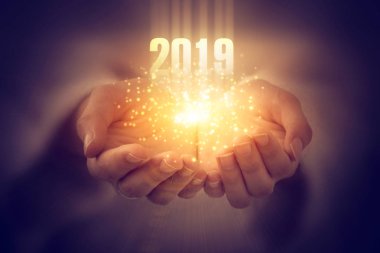 Yeni yıl 2019. Kadınların elleri yayılan sihirli enerji. Bokeh ve bir ışık ile karanlık arka plan