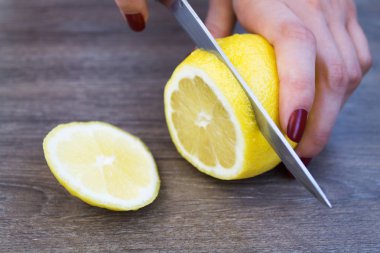 bir ahşap tahta üzerinde parçalar halinde kesip bir limon eller