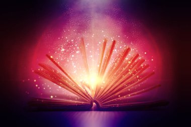 Karanlık bir arka plan üzerinde açık bir sihirli kitap.