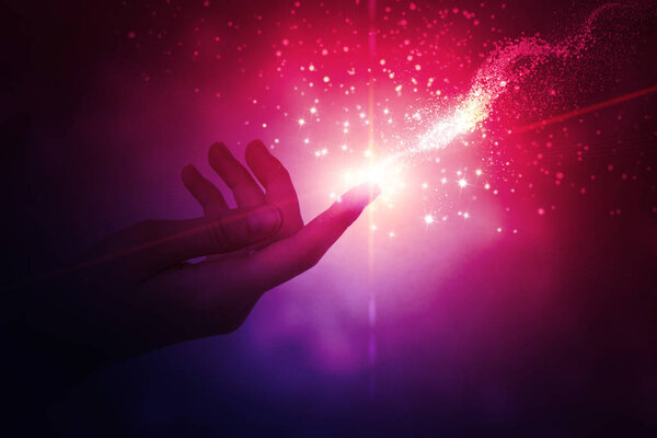 A female hand giving a stream of magical energy on a dark abstract background. The concept of magic and witchcraft