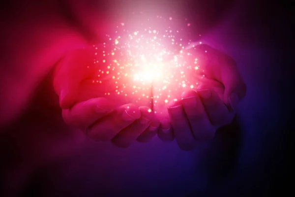 Sihirli parçacıklar, karanlık bir arka plan üzerinde eller yakın çekim gelen enerji akışını