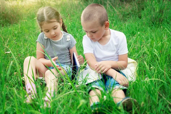 子供は 晴れた日に草の上に座るし 本を読みます 学校の準備 — ストック写真