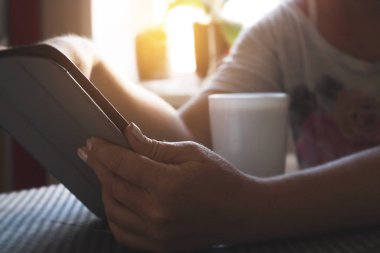 Kız bir tablet üzerinde çalışır, e-posta ile sabah görünüyor ve kahve içer