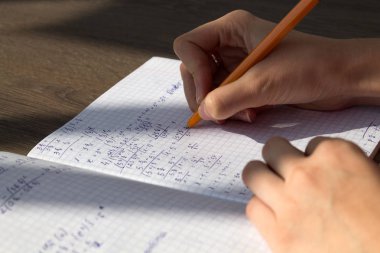 Bir el matematiksel formüller bir defterde yazar. Okul ödevi, matematik