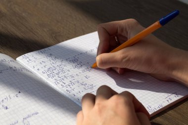 Bir el matematiksel formüller bir defterde yazar. Okul ödevi, matematik