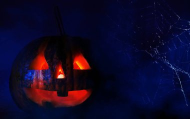 Cadılar Bayramı ile koyu arka plan. Bir örümcek ağı ile karanlık bir arka plan üzerinde gözleri yanma ile kabak