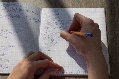 Bir el matematiksel formüller bir defterde yazar. Okul ödevi, matematik
