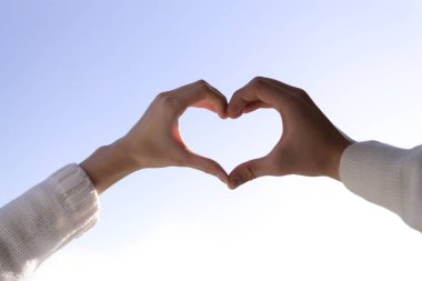 Yakışıklı bir erkek ve bir kadın gökyüzüne karşı bir kalp şeklinde. Aşk ve ilişki kavramı