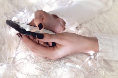 Bokeh ile beyaz bir arka plan üzerinde bir kadının elinde bir boş ekran cep telefonu arka plan