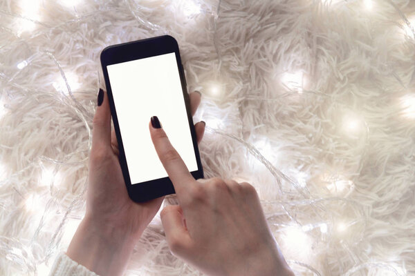 Background of a blank screen mobile phone in the hands of a woman on a white background with bokeh