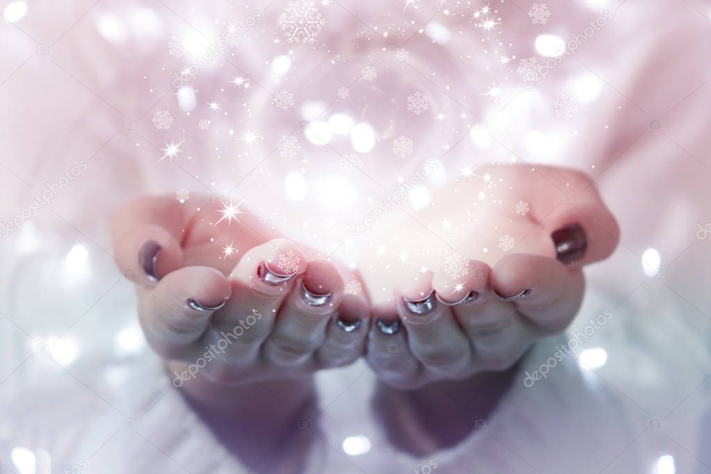 Magic particles emanating from female hands. Christmas background with bokeh