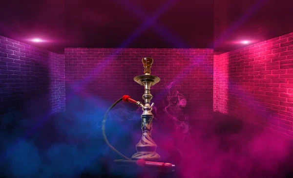 Курение кальян на фоне пустой комнаты. Разноцветный неоновый свет. Прожектор, лазерные голубые и розовые лучи, дым . — стоковое фото