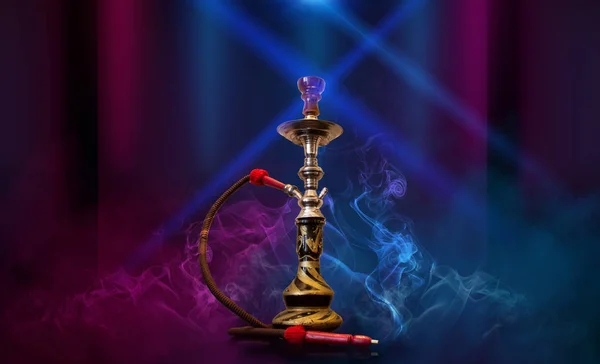 Smoking hookah on the background of an empty room. Multicolored neon light. Searchlight, laser blue and pink rays, smoke. — Stock Photo, Image