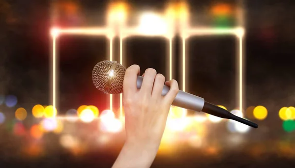 A female hand is holding one microphone against the colorful lights of the karaoke club scene. Bright colorful background with blurred neon lights — Stock Photo, Image
