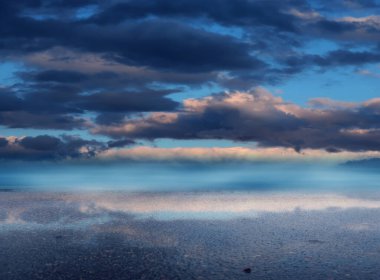 Gün batımında parlak mavi gökyüzü. Islak asfalt üzerinde bulutlarla gökyüzünün yansıması. Boş Sahne Arkaplanı