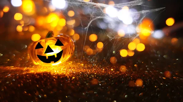 Neon glowing pumpkin head on abstract blurred bokeh background. Festive Halloween background with cobwebs and pumpkin.