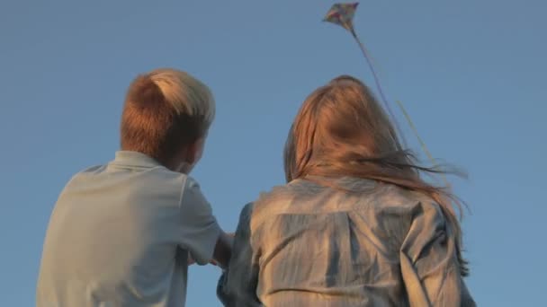 一个男孩和一个女孩在大风中放飞风筝 在背景下 风筝在天空中飞翔 — 图库视频影像